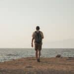 Backpacker kijkt uit over een bestemming bereikt op een klein reisbudget