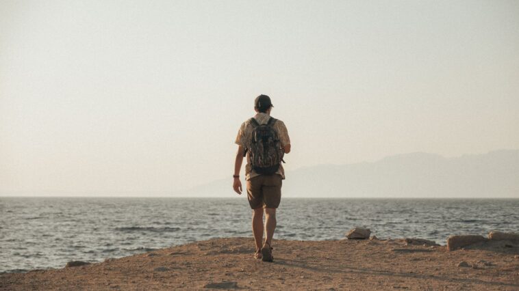 Backpacker kijkt uit over een bestemming bereikt op een klein reisbudget