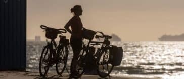 Reiziger op de fiets langs een kustweg tijdens zonsopgang