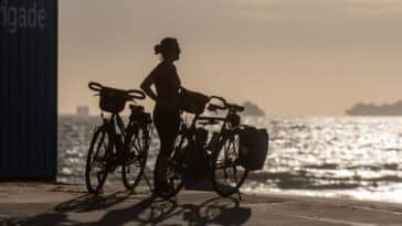 Reiziger op de fiets langs een kustweg tijdens zonsopgang
