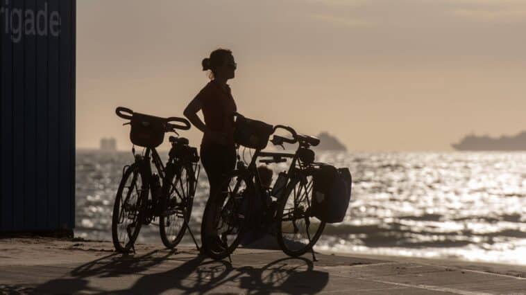 Reiziger op de fiets langs een kustweg tijdens zonsopgang
