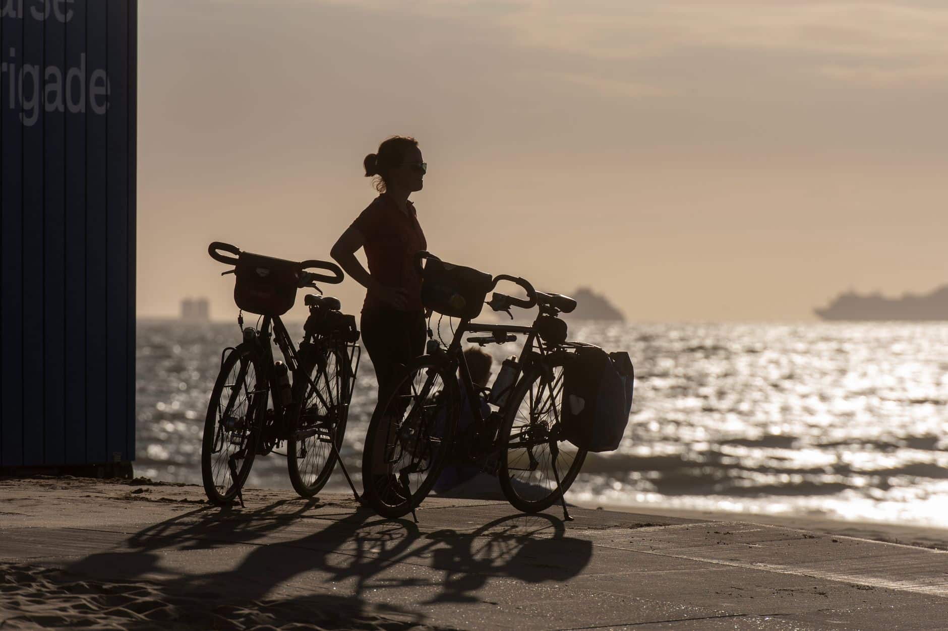 Reiziger op de fiets langs een kustweg tijdens zonsopgang