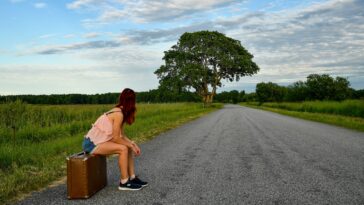 Vrouw met rugzak kijkt uit over een landschap tijdens een solo reis